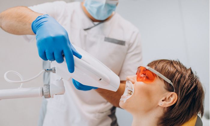 Zahnarzt führt Zahnbleaching bei einer Patientin aus