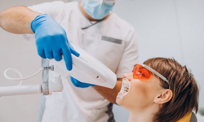 Zahnarzt führt Zahnbleaching bei einer Patientin aus